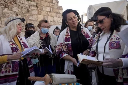 FILE - Members of Women of the Wall gather around a Torah scroll the group smuggled in for their Rosh Hodesh prayers marking the new month, at the Western Wall where women are forbidden from reading from the Torah, Sunday, Dec. 5, 2021. When Israel's new government took office last June, it indicated it would press ahead on an egalitarian prayer site at Jerusalem's Western Wall — a sensitive holy site that has emerged as a point of friction between Jews over how prayer is conducted there. (AP 