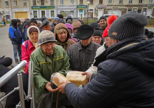 Local residents stand in line waiting for free bread from volunteers in Bakhmut, the site of the heaviest battle against the Russian troops in the Donetsk region, Ukraine, Friday, Oct. 28, 2022. (AP Photo/Efrem Lukatsky)