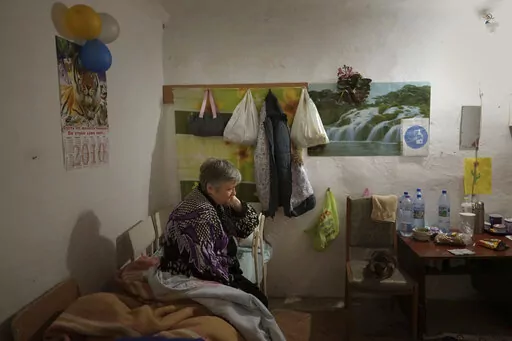 Natalia sits on a makeshift bed, on a shelter builded on the ground floor of her building in Mykolaiv downtown, Ukraine, Monday, Oct. 24, 2022. With the Russian invasion in its ninth month, many Ukrainians no longer ask if their country will be hit by nuclear weapons. They are actively preparing for that once-unthinkable possibility. (AP Photo/Emilio Morenatti)