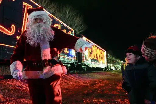 Santa Claus waves to children during a visit of the CSX Holiday Express Thursday, Nov. 21, 2024, in Erwin, Tenn. The railway company held a celebration and concert for the town affected by Hurricane Helene. (AP Photo/George Walker IV)
