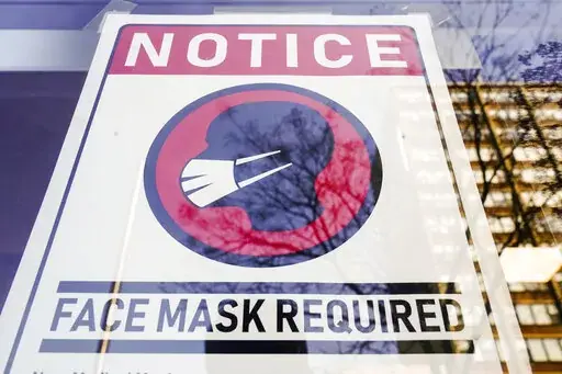 A sign requiring masks as a precaution against the spread of the coronavirus is posted on a store front in Philadelphia, on Feb. 16, 2022. The Biden administration will significantly loosen federal mask-wearing guidelines to protect against COVID-19 transmission on Friday, according to two people familiar with the matter. (AP Photo/Matt Rourke, File)