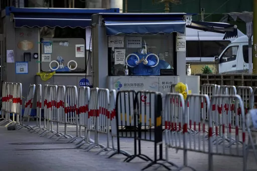 Workers in protective gear wait to administer a COVID-19 test at a quiet coronavirus testing site in Beijing, Sunday, Dec. 11, 2022. Facing a surge in COVID-19 cases, China is setting up more intensive care facilities and trying to strengthen hospitals as Beijing rolls back anti-virus controls that confined millions of people to their homes, crushed economic growth and set off protests. (AP Photo/Andy Wong)