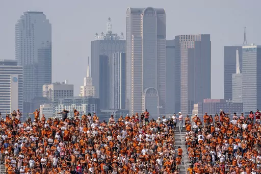 The Dallas skyline rises behind the Cotton Bowl stands as Texas fans watch during the first half of an NCAA college football game against Oklahoma at the Cotton Bowl, Saturday, Oct. 8, 2022, in Dallas. U.S. metropolitan areas increased their populations by almost half a percent last year in another sign that flight from urban areas during the first year of the pandemic either slowed down or reversed in its second year as people moved to Sunbelt metros in Texas and Florida by the tens of thousand
