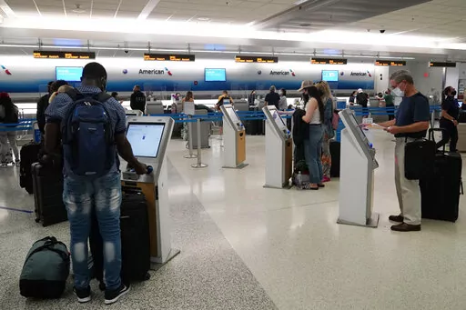 Travelers use the self-service kiosk to check in and pay for luggage at the American Airlines terminal, Thursday, April 29, 2021, in Miami.  Driven in part by pressure for contactless interactions during the pandemic, technology is rapidly evolving in the travel industry.  (AP Photo/Marta Lavandier, File)