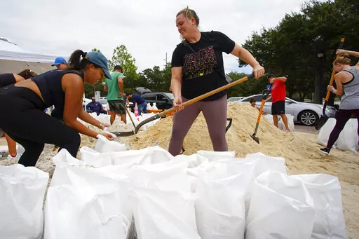 Friends Felicia Livengood, 29, and Victoria Colson, 31, fill sandbags along with hundreds of other Tampa, residents that waited for over 2 hours at Himes Avenue Complex to fill their 10 free sandbags on Sunday, Sept. 25, 2022, in Tampa, Fla. (Luis Santana/Tampa Bay Times via AP)