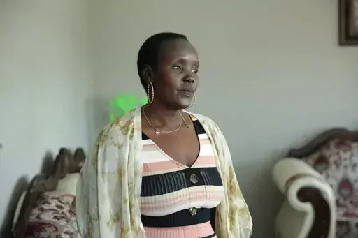 Achut Deng, a refugee from South Sudan, poses in her home in Sioux Falls, S.D., on Sept. 17, 2022, before the release of her memoir, “Don’t Look Back.” Deng shared her experience of being sickened with COVID-19 alongside hundreds of her coworkers at a pork processing plant. She shares her story of fleeing massacres and surviving a refugee story in her book. (AP Photo/Stephen Groves)