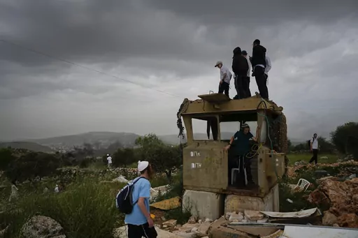 Israeli settlers stand in the outpost of Eviatar in the West Bank, Monday, April 10, 2023. Thousands led by hardline ultranationalist Jewish settlers marched to the unauthorized settlement outpost Eviatar in the northern West Bank that was cleared by the Israeli government in 2021, protected by a large contingent of Israeli soldiers and police. (AP Photo/Ariel Schalit)