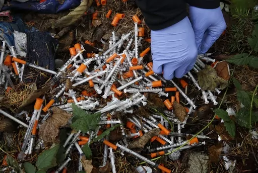 A volunteer cleans up needles used for drug injection that were found at a homeless encampment in Everett, Wash., Nov. 8, 2017. A temporary law that makes possession of small amounts of drugs a misdemeanor expires on July 1, so if lawmakers fail to pass a bill, Washington would become the second state — after neighboring Oregon — to decriminalize drug possession. Lawmakers said Tuesday, May 2, 2023, they were increasingly optimistic a compromise will be reached to avoid those consequences. (