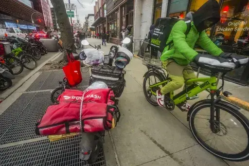 A food delivery worker rides down a sidewalk after a pickup from a restaurant in New York on Jan. 29, 2024. DoorDash is stepping up efforts to stop delivery drivers who are breaking traffic laws. (AP Photo/Bebeto Matthews, FILE)
