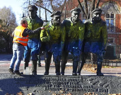 Workers clean a monument that was defaced with the blue and yellow colors of the Ukrainian flag, in Krakow, Poland, Nov. 6, 2021. Days before Poland’s Independence Day vandals painted the blue-and-yellow colors of the Ukrainian flag on monuments. The vandalism, which took place as Russia massed troops near Ukraine’s border, looked as if Ukrainians were defacing memorials to Polish national heroes. Though prosecutors are still investigating, Polish and Ukrainian authorities believe it was mos