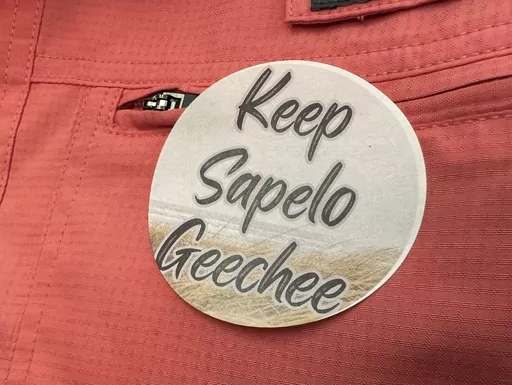 A sticker saying "Keep Sapelo Geechee" is worn on the shirt of George Grovner, a resident of the Hogg Hummock community on Sapelo Island, during a meeting of McIntosh County commissioners, Sept. 12, 2023, in Darien, Ga. A lawsuit by Black descendants of slaves that challenges zoning changes affecting their island homes is before a Georgia judge, who must decide whether to allow lawyers to amend the civil complaint to avoid having it dismissed. (AP Photo/Ross Bynum, File)