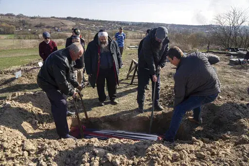 Funeral workers lower the coffin of Zoreslav Zamoiskiy, killed by Russian troops in the town of Bucha as Moshe Reuven Azman, Rabbi of Ukraine stands in center at the Jewish cemetery near Vasylkiv, Ukraine, on Friday, April 15, 2022. The final hours before Passover found the chief rabbi for Kyiv and Ukraine in a cemetery. Before he could mark the Jewish people’s escape from slavery in Egypt thousands of years ago, he was burying a man who didn’t escape a Russian bullet. (AP Photo/Evgeniy Malo