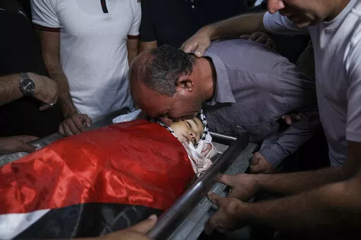 Father of 7-year-old Palestinian boy Rayan Suleiman, kisses his body at a hospital in the West Bank village of Beit Jala just before his funeral Friday, Sept. 30, 2022. The U.S. State Department has called on Israel to open a "thorough" investigation into the mysterious death of the boy, who collapsed and died shortly after Israeli soldiers came to his home in the occupied West Bank. Relatives said he had no previous health problems and accused the army of scaring the child to death. The army ca