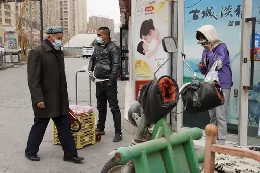 In this March 18, 2021, file photo, residents wearing masks walk along the streets of Aksu in western China's Xinjiang region. (AP Photo/Ng Han Guan, File)