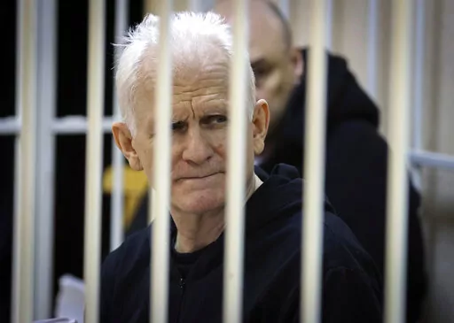 Ales Bialiatski, the head of Belarusian Vyasna rights group, sits in a defendants' cage during a court session in Minsk, Belarus, on Thursday Jan. 5, 2023. A Belarusian court has sentenced Ales Bialiatski, Belarus' top human rights advocate and one of the winners of the 2022 Nobel Peace Prize, to 10 years in prison. Bialiatski and three other top figures of the Viasna human rights center he founded were convicted of financing anti-government protests. (Vitaly Pivovarchyk/BelTA Pool Photo via AP,