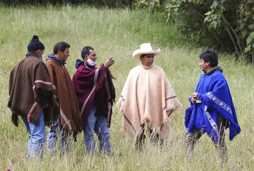 Free Peru party presidential candidate Pedro Castillo, wearing a hat and poncho, talks to neighbors in Chugur, in the Andes of Peru, April 15, 2021. When Castillo won Peru’s presidency, it was celebrated as a victory by the country’s poor — the peasants and Indigenous people who live deep in the Andes and whose struggles had long been ignored. (AP Photo/Martin Mejia, File)