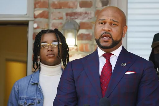 CORRECTS SPELLING OF FIRST NAME TO D’MONTERRIO - FedEx driver D'Monterrio Gibson, left, stands next to his attorney, Carlos Moore, during a news conference in Ridgeland, Miss., Thursday, Feb. 10, 2022. Gibson and his attorneys say the delivery driver was shot at and chased by a white father and son in Brookhaven while making deliveries, and that both suspects have been "undercharged" and call upon the authorities to instead charge the pair with attempted murder and hate crimes. (AP Photo/Rogel