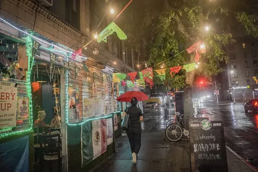 A restaurant's pandemic-era outdoor dining, left, extends onto a sidewalk in Brooklyn's Flatbush neighborhood, Monday Aug. 7, 2023, in New York. New York City's roadway dining sheds, a pandemic innovation, are coming under new rules for design and seasonality. (AP Photo/Bebeto Matthews)