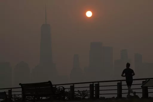 A man runs in front of the sun rising over the lower Manhattan skyline in Jersey City, N.J., June 8, 2023. Thick, smoky air from Canadian wildfires made for days of misery in New York City and across the U.S. Northeast this week. But for much of the rest of the world, breathing dangerously polluted air is an inescapable fact of life — and death. (AP Photo/Seth Wenig, File)