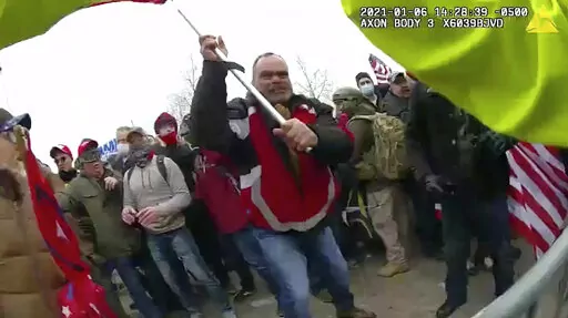 This still frame from Metropolitan Police Department body worn camera video shows Thomas Webster, in red jacket, at a barricade line at on the west front of the U.S. Capitol on Jan. 6, 2021, in Washington. Retired New York City police officer Webster is the next to go on trial, with jury selection scheduled to begin Monday, April 25, 2022. Webster has claimed he was acting in self-defense when he tackled a police officer who was trying to protect the Capitol from a mob on Jan. 6. (Metropolitan P