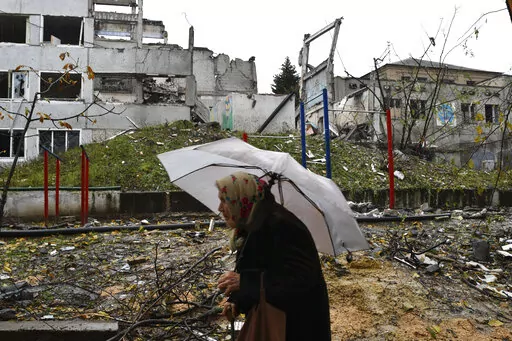 A woman walks past buildings damaged by Russian shelling in Druzhkivka, Donetsk region, Ukraine, Wednesday, Oct. 26, 2022. (AP Photo/Andriy Andriyenko)