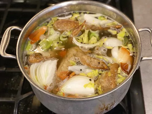 Vegetables and turkey parts cook on a stove to make turkey stock in New Milford, Conn. in November 2022. (Katie Workman via AP)