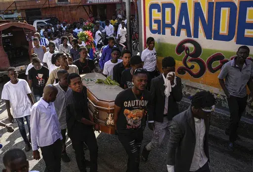 Friends and family accompany the coffin that contain the remains of Jhon-Roselet Joseph, killed by a stray bullet during clashes between police, and gang members who were trying to invade the Solino neighborhood, during a funeral procession in Port-au-Prince, Haiti, Saturday, May 18, 2024 (AP Photo/Ramon Espinosa)