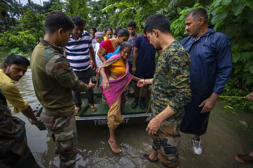 Indian army personnel rescue flood-affected villagers on a boat in Jalimura village, west of Gauhati, India, Saturday, June 18, 2022. More than a dozen people have died as massive floods ravaged northeastern India and Bangladesh, leaving millions of homes underwater and severing transport links, authorities said Saturday. (AP Photo/Anupam Nath)