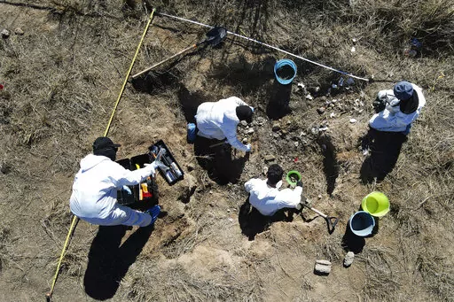 Forensic technicians excavate a field on a plot of land referred to as a cartel "extermination site" where burned human remains are buried, on the outskirts of Nuevo Laredo, Mexico, Tuesday, Feb. 8, 2022. The  insufficiency of investigations into Mexico’s nearly 100,000 disappearances is evident. There are 52,000 unidentified people in morgues and cemeteries, not counting places like this one, where the charred remains are measured only by weight. (AP Photo/Marco Ugarte)