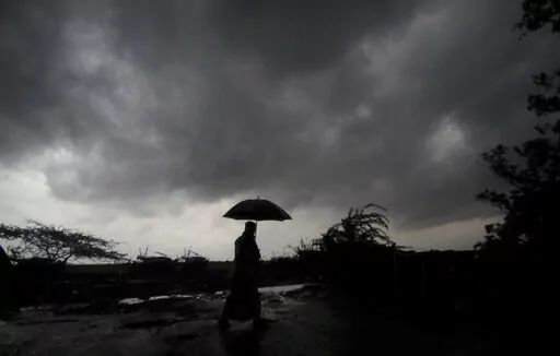 A villager holds an umbrella as dark clouds loom over Balasore district in Odisha, India, Tuesday, May 25, 2021, ahead of a powerful storm barreling toward the eastern coast. When it comes to measuring global warming, it’s not just the heat, it’s the humidity that matters in dangerous climate extremes, according to a study released on Monday, Jan. 31, 2022, in the Proceedings of the National Academy of Sciences in the U.S. (AP Photo/File)