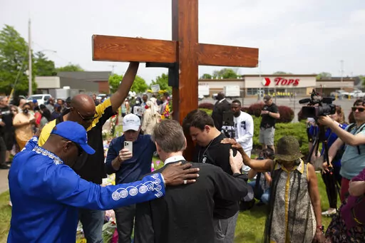 A group prays at the site of a memorial for the victims of the Buffalo supermarket shooting outside the Tops Friendly Market on Saturday, May 21, 2022, in Buffalo, N.Y.   Tops was encouraging people to join its stores in a moment of silence to honor the shooting victims Saturday at 2:30 p.m., the approximate time of the attack a week earlier. Buffalo Mayor Byron Brown also called for 123 seconds of silence from 2:28 p.m. to 2:31 p.m., followed by the ringing of church bells 13 times throughout t