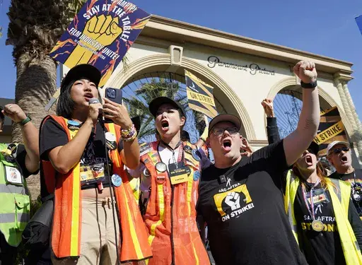 SAG-AFTRA captains Iris Liu, left, and Miki Yamashita, center, and SAG-AFTRA chief negotiator Duncan Crabtree-Ireland lead a cheer for striking actors outside Paramount Pictures studio, Nov. 3, 2023, in Los Angeles. Hollywood's video game performers voted to go on strike Thursday, July 25, 2024, throwing part of the entertainment industry into another work stoppage after talks for a new contract with major game studios broke down over artificial intelligence protections. (AP Photo/Chris Pizzello