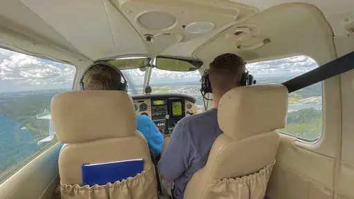 In this photo provided by Kaitlin Marie Sells, Sam Lilley, left, pilots a small airplane that took off from Savannah, Ga., on Aug, 6, 2022, for a flight to reach the 1,500 flight hours required for Lilley to begin training to become an airline pilot. (Kaitlin Marie Sells via AP)