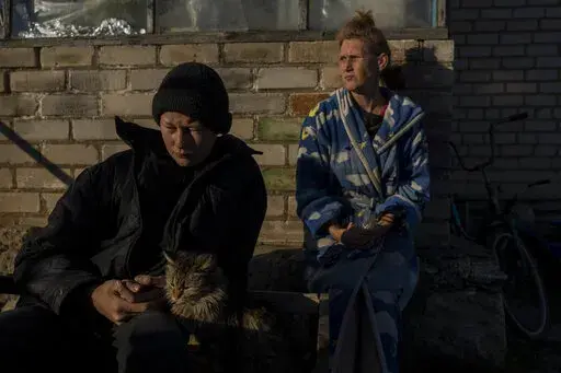 Vitaliy Mysharskiy, 14, left, and his grandmother Tanya Babii sit in the yard of the family house in the recently liberated village of Kyselivka, outskirts of Kherson, southern Ukraine, Tuesday, Nov. 15, 2022. As violence escalates in Ukraine abuse has become widespread, according to the United Nations. In September Alesha Babenko and his 14-year-old nephew, Vitaliy Mysharskiy, were arrested by Russian soldiers who occupied their small village of Kyselivka, after taking photos of destroyed tanks