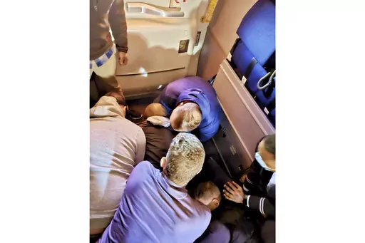 This image provided by Simik Ghookasian shows passengers and crew members restraining a man who according to federal authorities tried to open an airliner’s emergency door and tried to stab a flight attendant on a weekend flight from Los Angeles to Boston on Sunday, March 5, 2023. Simik Ghookasian, a passenger, said in a telephone interview that he was seated several rows behind the suspect, identified by federal authorities as Francisco Severo Torres, when he heard a commotion. (Simik Ghookas