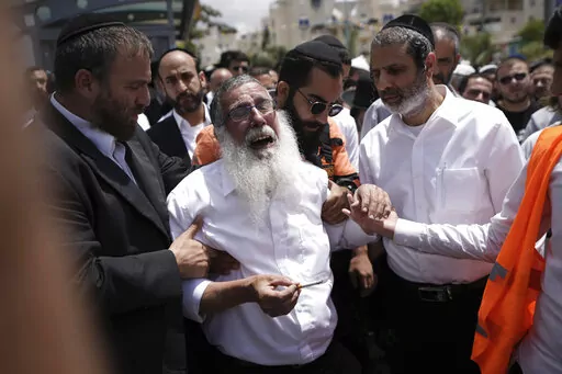 Ultra-Orthodox Jewish mourners encircle a man overcome with grief at the funeral for Yonatan Havakuk and Boaz Gol, a day after they were killed in a stabbing attack in Elad, Israel, Friday, May 6, 2022. Israeli security forces waged a massive manhunt Friday for two Palestinians suspected of carrying out the stabbing attack on Thursday near Tel Aviv that left three Israelis dead. (AP Photo/Ariel Schalit)