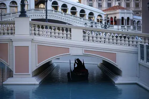 A gondolier steers his boat beneath a quiet pedestrian walkway at the Venetian hotel and casino in Las Vegas on Feb. 4, 2021. (AP Photo/John Locher, File)