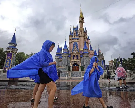Guests at the Magic Kingdom at Walt Disney World brave wind and rain as bands of weather from Hurricane Debby pass through Central Florida, Monday, Aug. 5, 2024, in Bay Lake, Fla. (Joe Burbank/Orlando Sentinel via AP)