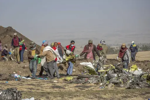 Debris is carried at the scene of an Ethiopian Airlines flight crash near Bishoftu, or Debre Zeit, south of Addis Ababa, Ethiopia, on March 11, 2019. A spokesman says Ethiopian Airlines has grounded all its Boeing 737 Max 8 aircraft as a safety precaution, following the crash of one of its planes in which 157 people were killed. (AP Photo/Mulugeta Ayene)