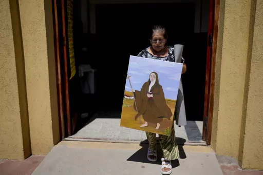 Rita Canteros walks out of a parish church carrying a painting of María Antonia de Paz y Figueroa, more commonly known by her Quechua name of “Mama Antula,” on the outskirts of Buenos Aires, Argentina, Sunday, Jan. 28, 2024. The canonization of “Mama Antula” in a Feb. 11th ceremony to be presided by Pope Francis at St. Peter's Basilica marks the first time a female from Argentina will become saint. (AP Photo/Natacha Pisarenko)