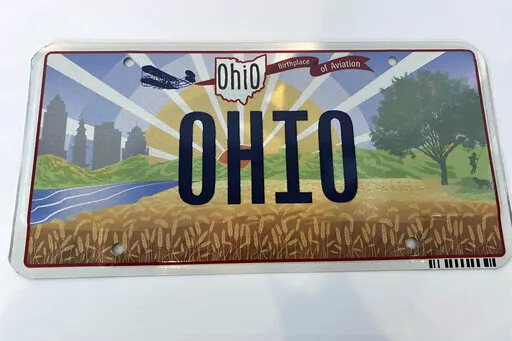 Ohio Gov. Mike DeWine on Thursday, Oct. 21, 2021, unveiled the new "Sunrise in Ohio" license plate in Columbus, Ohio. A backwards image of the Wright Flyer that appeared on the initial version of Ohio’s new license plate was added to the design early and never changed or questioned throughout the approval process, according to public records obtained by The Associated Press. The error was fixed only after the public unveiling in October drew attention to it. (Jessie Balmert/The Cincinnati Enqu