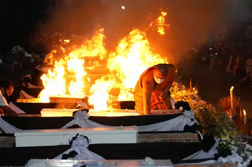 A monk lights funeral pyres to cremate those who died in the day care center attack at Wat Rat Samakee temple in Uthai Sawan, northeastern Thailand, Tuesday, Oct. 11, 2022. A former police officer burst into a day care center in northeastern Thailand on Thursday, killing dozens of preschoolers and teachers before shooting more people as he fled. (AP Photo/Sakchai Lalit)