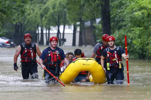 Members of the Balch Springs Fire Department bring a family of four by boat to higher ground after rescuing them from their home along Forest Glen Lane in Batch Springs, Texas, Aug. 22, 2022. This summer the weather has not only been extreme, but it has whiplashed from one extreme to another. Dallas, St. Louis, Kentucky, Yellowstone, Death Valley all lurched from drought to flood. (Elías Valverde II/The Dallas Morning News via AP, File)/The Dallas Morning News via AP)