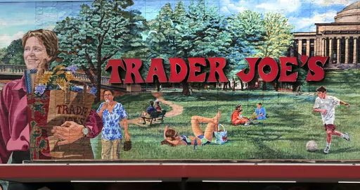 The Trader Joe's logo hangs on a mural, Aug. 13, 2019, in Cambridge, Mass. Trader Joe's recently upped the price to 23 cents for a single banana, marking a 4-cent increase from the grocer's previous going rate for the fruit that remained unchanged for over 20 years. (AP Photo/Charles Krupa, File)