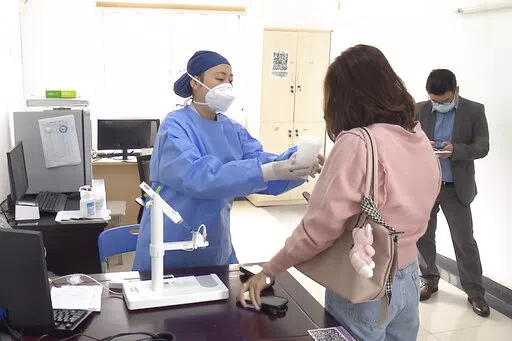 In this photo taken from video released by Shanghai Media Group, a medical worker hands over aerosolised COVID vaccine developed by Chinese biopharmaceutical company CanSino Biologics Inc. in Shanghai on Wednesday, Oct. 26, 2022. The Chinese city of Shanghai started administering the inhalable COVID-19 vaccine on Wednesday in what appears to be a world first. (Shanghai Media Group via AP)