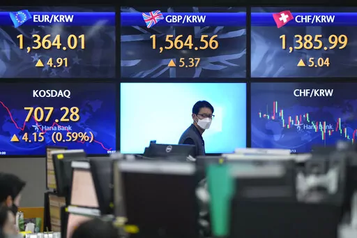 A currency trader walks by the screens showing the foreign exchange rates at a foreign exchange dealing room in Seoul, South Korea, Wednesday, Dec. 21, 2022. Shares were mixed in Asia on Wednesday after a modestly higher close on Wall Street as concerns over pressures on global growth tempered gains in the absence of major data releases. (AP Photo/Lee Jin-man)