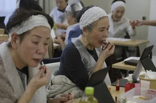 Women try on the lipstick of the color they like as they take part in a special makeup class at a community center room in Tokyo, on Feb. 14, 2025. (AP Photo/Yuri Kageyama)