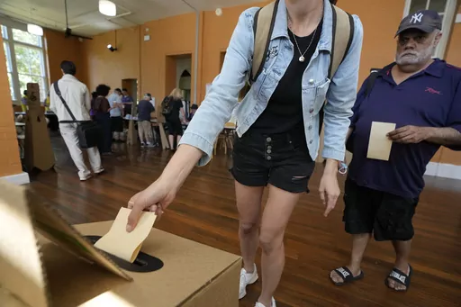 A man, right, waits as a woman drops her ballot into a box a polling place in Redfern as Australians cast their final votes in Sydney, Saturday, Oct. 14, 2023, in their first referendum in a generation that aims to tackle Indigenous disadvantage by enshrining in the constitution a new advocacy committee. Australia will look for new ways to lift Indigenous living standards after voters soundly rejected a proposal to create a new advocacy committee, the deputy prime minister said on Sunday, Oct. 1