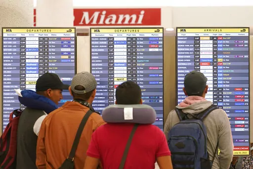 Travelers check their flights at Miami International Airport, Saturday, July 2, 2022, in Miami. The Fourth of July holiday weekend is jamming U.S. airports with the biggest crowds since the pandemic began in 2020. (AP Photo/Marta Lavandier)