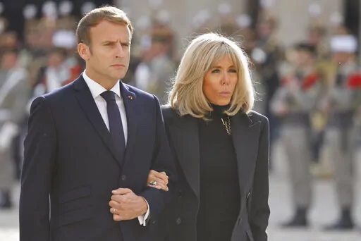 FILE. French President Emmanuel Macron and his wife Brigitte Macron attend a national memorial ceremony for Hubert Germain at the Hotel des Invalides, Friday Oct.15, 2021 in Paris. A group of "atypical journalists," on the autism spectrum, got France's 45-year-old president to talk about himself with unusual and illuminating candour in a televised interview this weekend. (Ludovic Marin, Pool Photo via AP)
